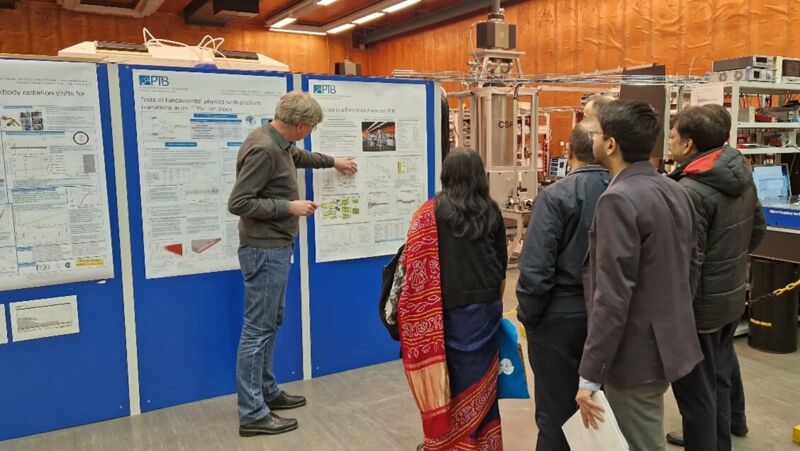 A group of people stand in front of a man who points to a poster he is presenting.