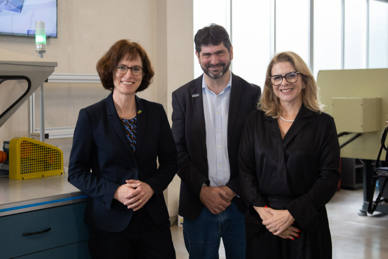 Drei Menschen schauen lächelnd in die Kamera.