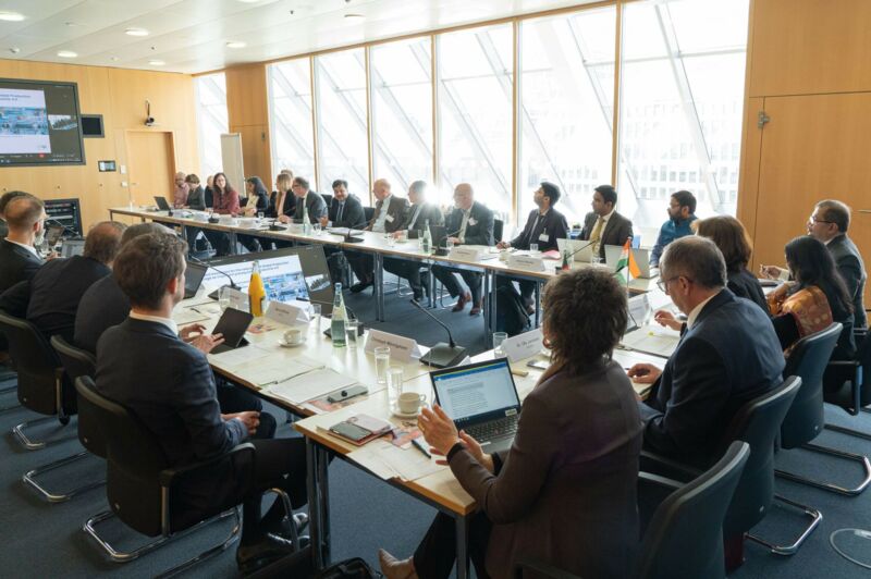 People sit together at a table and look at a screen.