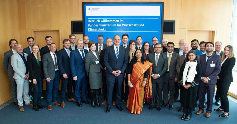 People pose together in front of the BMWK logo.