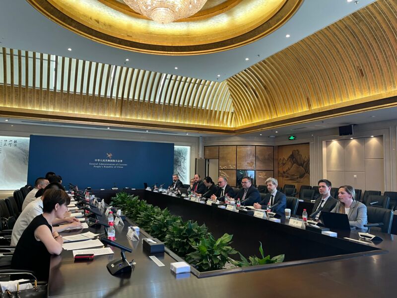 Menschen in einem Versammlungsraum sitzen sich an einem Tisch gegenüber.