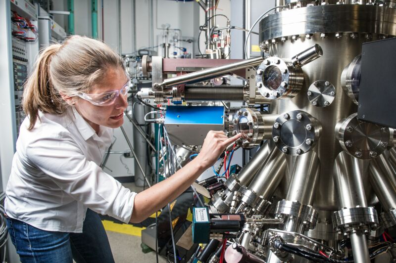 Woman with safety glasses examines an industrial machine